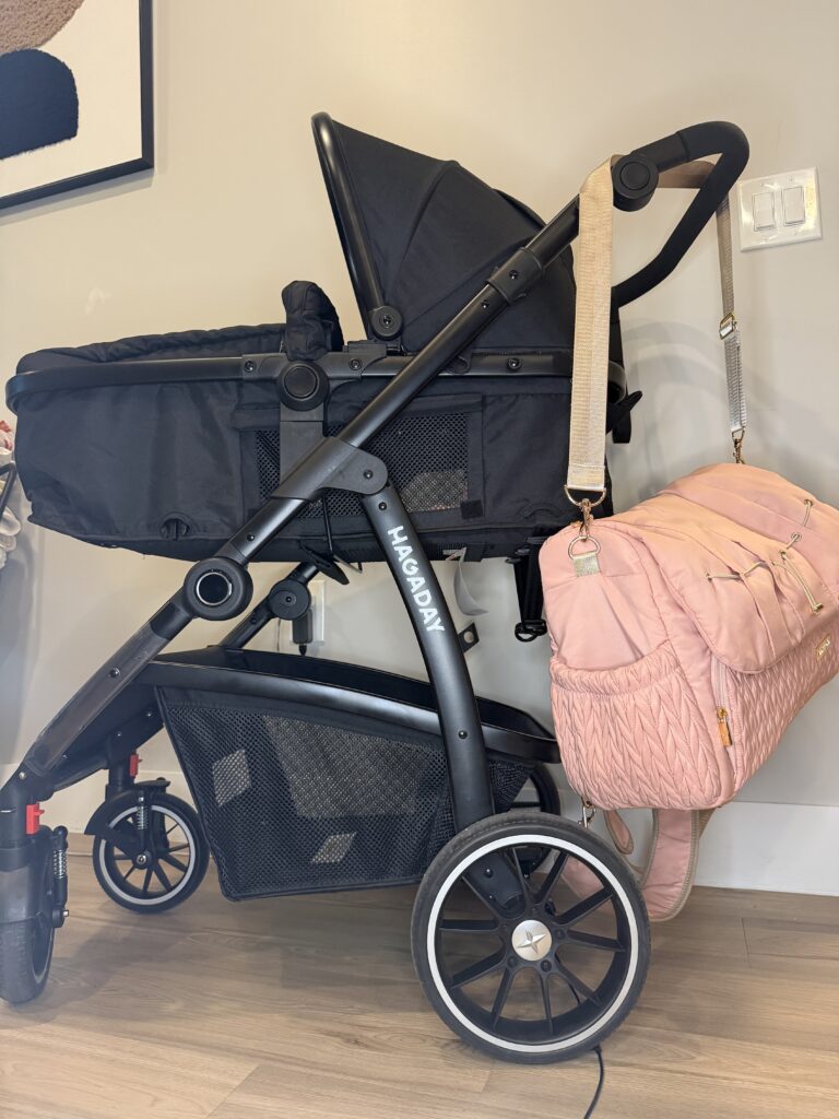 A chic baby diaper bag resting next to a modern baby stroller travel system.