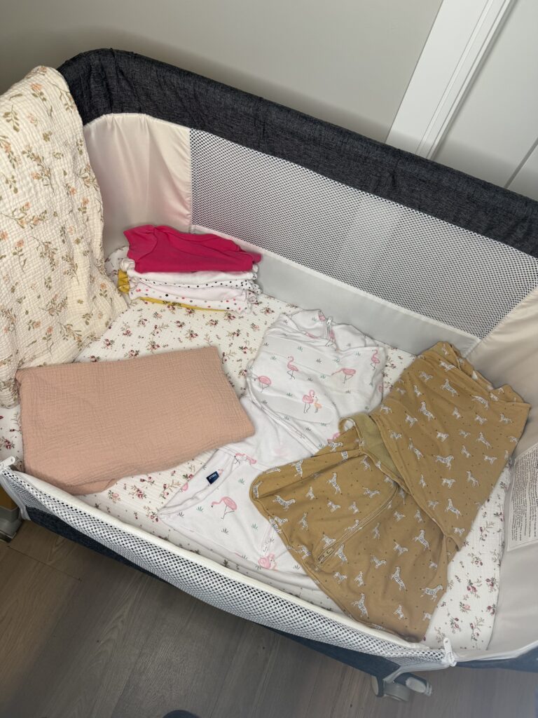 Two Halo sleep sacks with flamingo and zebra prints next to a stack of newborn onesies.